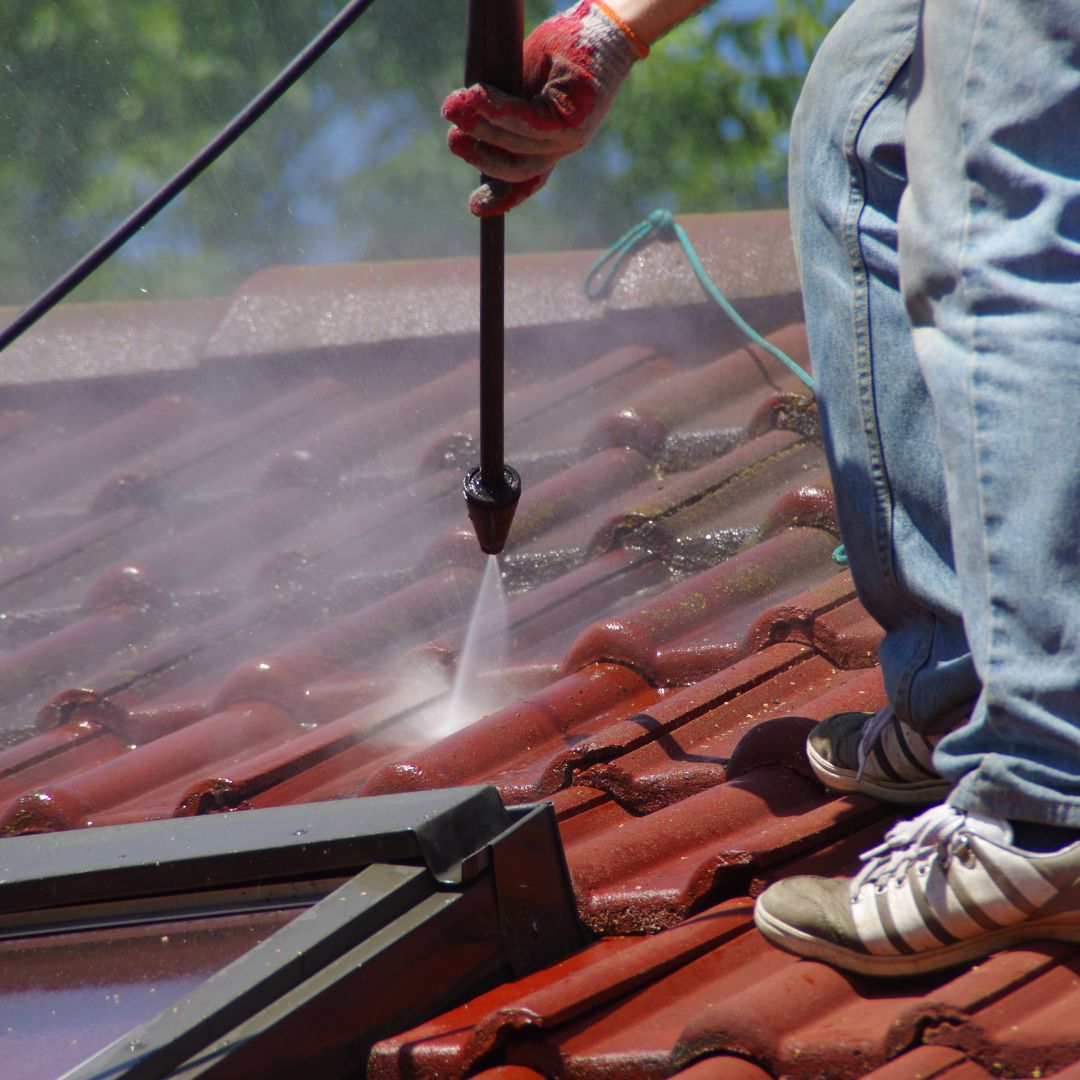 person power washing a roof